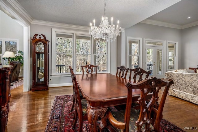 dining room featuring a textured ceiling, wood finished floors, baseboards, and ornamental molding