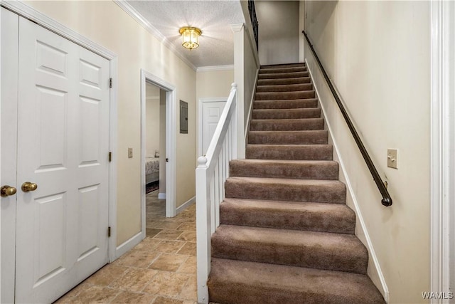 stairs with crown molding, stone finish floor, baseboards, and a textured ceiling