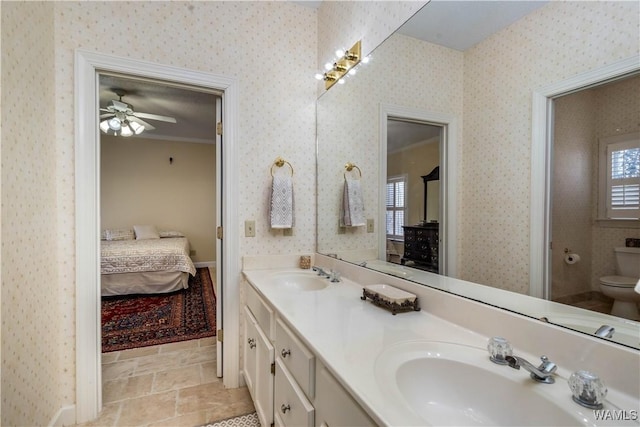 bathroom featuring a sink, connected bathroom, and wallpapered walls