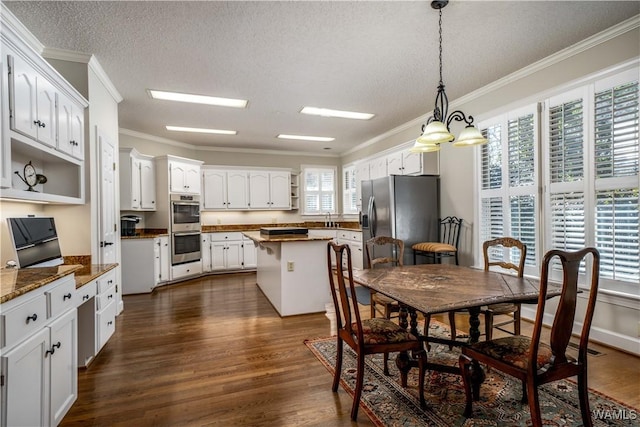 dining area featuring dark wood-style floors, a textured ceiling, and ornamental molding