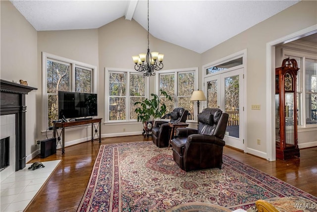 living room with wood finished floors, baseboards, beam ceiling, a fireplace, and a notable chandelier