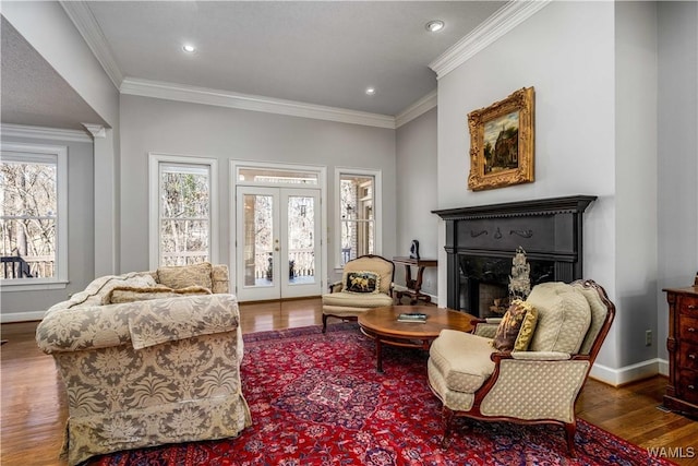 living area with crown molding, baseboards, french doors, a fireplace, and wood finished floors