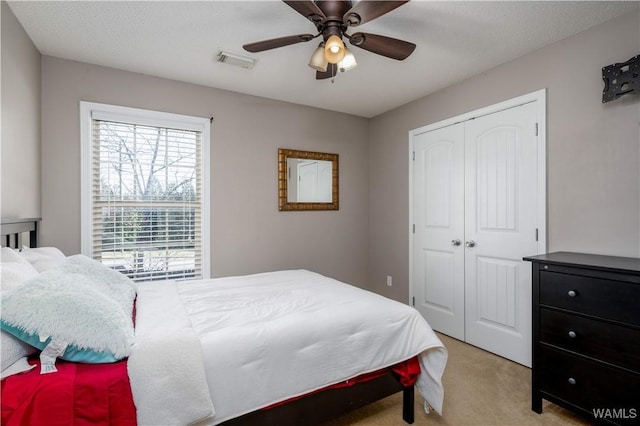 bedroom featuring visible vents, light carpet, a closet, and ceiling fan