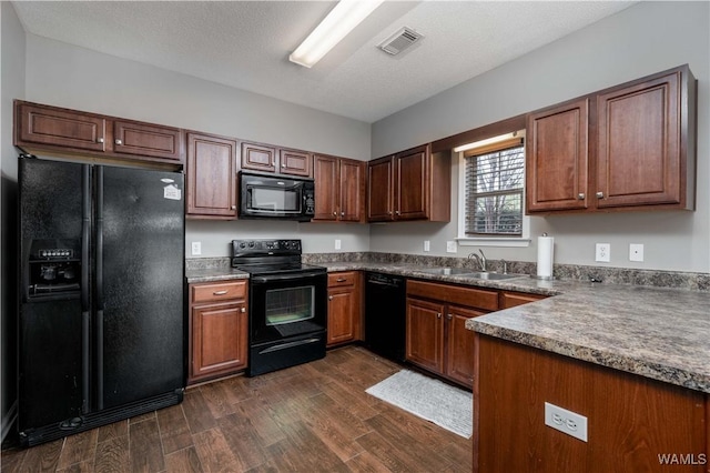 kitchen with black appliances, dark wood-style floors, visible vents, and a sink