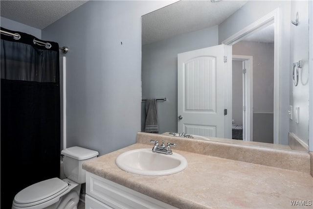 full bathroom with a textured ceiling, toilet, and vanity