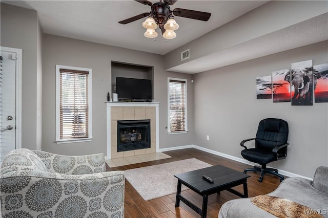 living room featuring a healthy amount of sunlight, visible vents, dark wood-style flooring, and baseboards