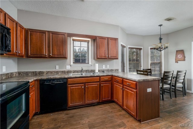 kitchen with visible vents, dark wood-type flooring, a peninsula, black appliances, and a sink