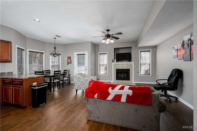 living room featuring dark wood finished floors, a textured ceiling, baseboards, and a tile fireplace