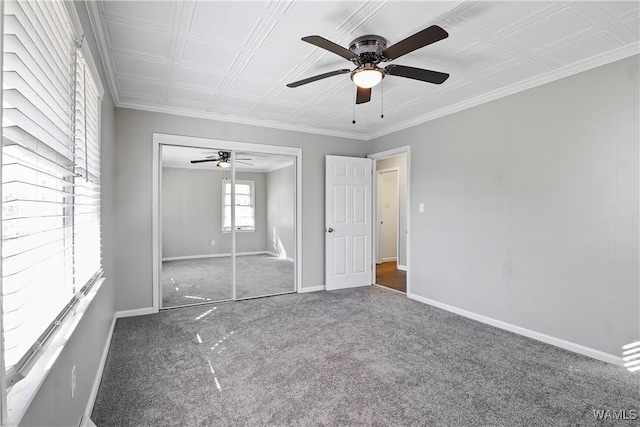 unfurnished bedroom featuring ceiling fan, ornamental molding, dark carpet, and a closet