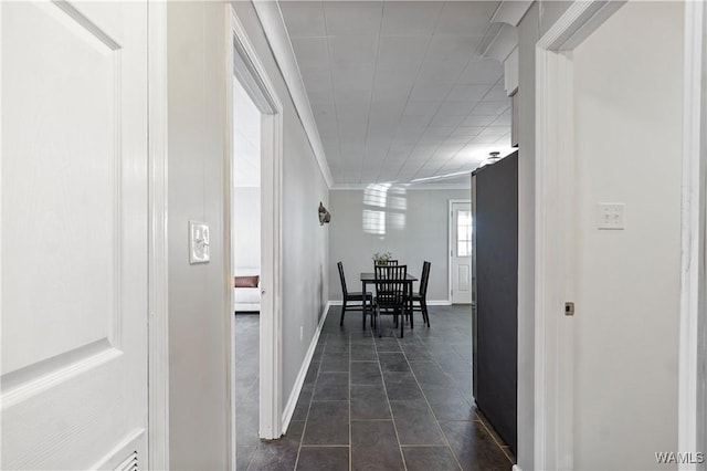 corridor featuring ornamental molding and dark tile patterned flooring