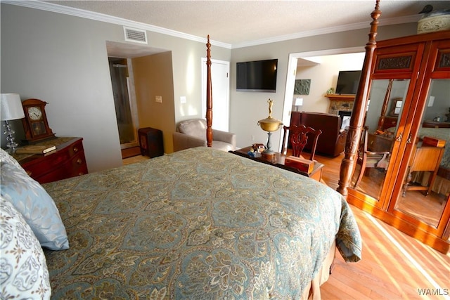 bedroom with a fireplace, light hardwood / wood-style floors, and crown molding