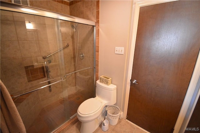 bathroom featuring tile patterned flooring, a shower with door, and toilet