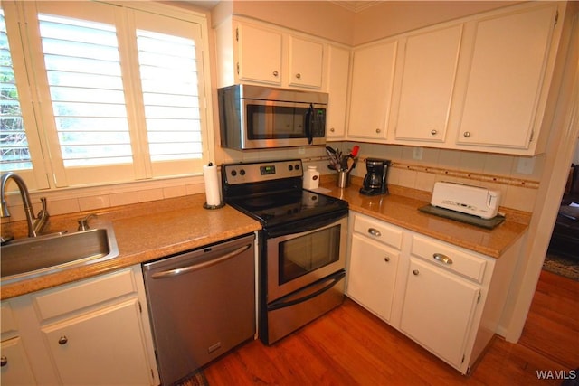 kitchen featuring white cabinets, sink, plenty of natural light, wood-type flooring, and stainless steel appliances