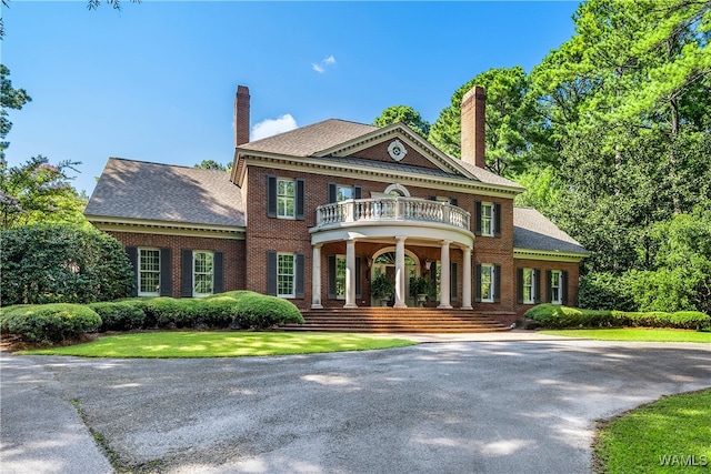 greek revival inspired property featuring a porch and a balcony