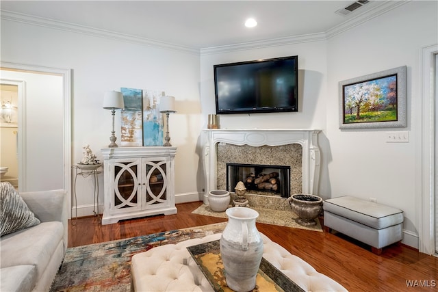 living room with hardwood / wood-style floors, ornamental molding, and a high end fireplace