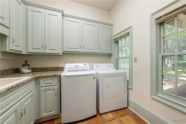 clothes washing area featuring a healthy amount of sunlight, cabinets, sink, and washing machine and dryer