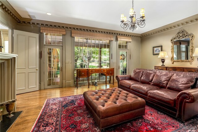 living room with a notable chandelier, light hardwood / wood-style floors, and crown molding