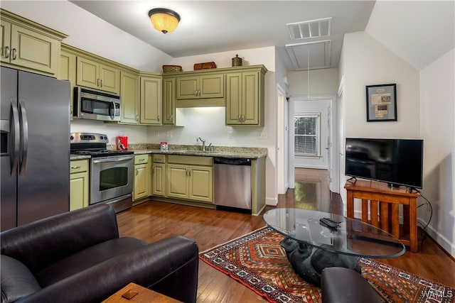 kitchen with appliances with stainless steel finishes, vaulted ceiling, dark wood-type flooring, sink, and green cabinetry