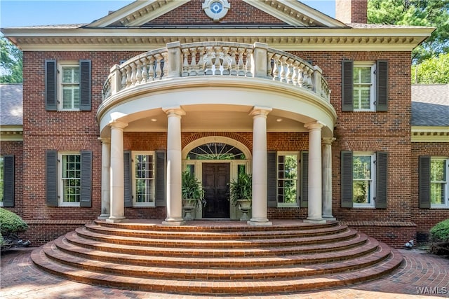 view of exterior entry with a balcony