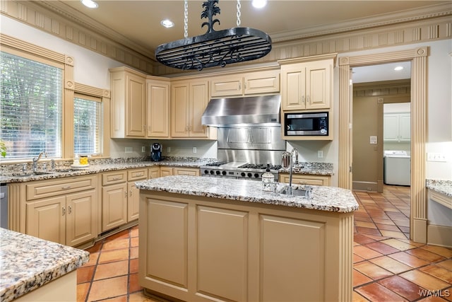 kitchen featuring cream cabinetry, appliances with stainless steel finishes, washer / clothes dryer, and crown molding