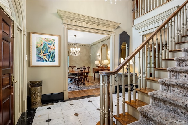 entrance foyer featuring ornamental molding, a towering ceiling, light hardwood / wood-style flooring, and a notable chandelier