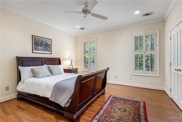 bedroom with ceiling fan, wood-type flooring, ornamental molding, and a closet