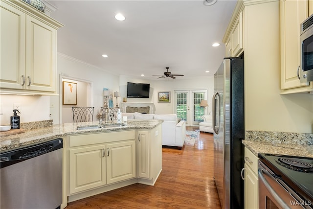 kitchen with appliances with stainless steel finishes, french doors, ornamental molding, cream cabinets, and light hardwood / wood-style floors