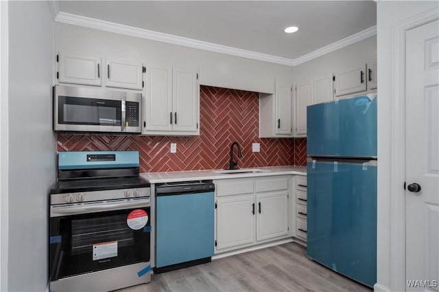 kitchen featuring stainless steel appliances, a sink, light countertops, and white cabinetry