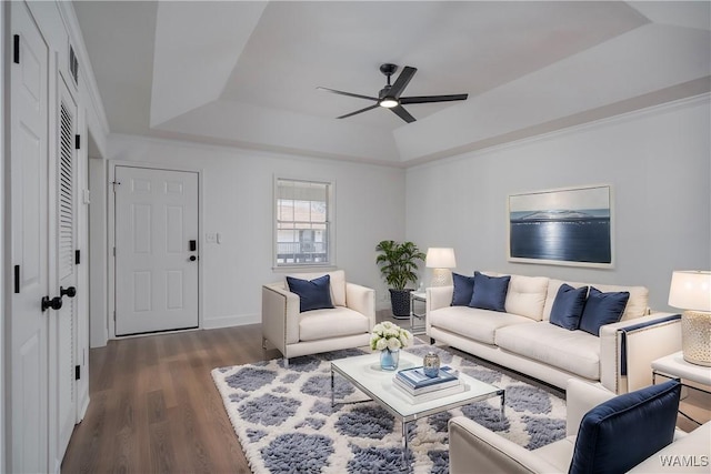 living room featuring dark wood-style floors, ceiling fan, a tray ceiling, and ornamental molding