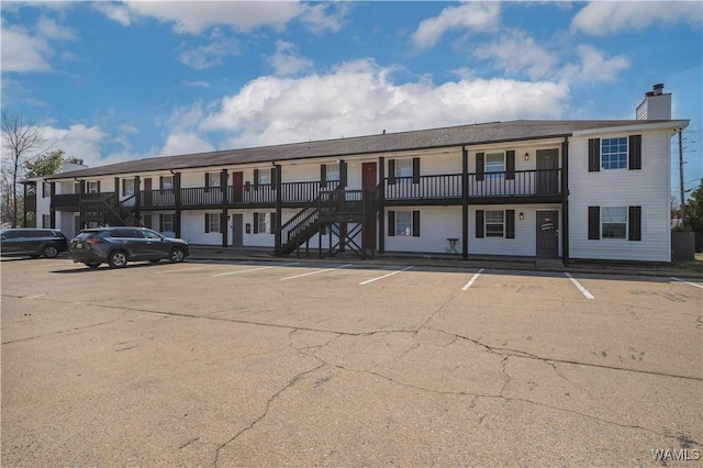 view of building exterior featuring stairs and uncovered parking