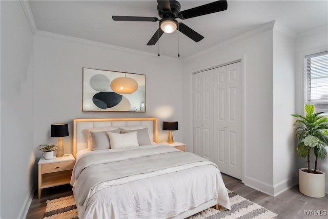 bedroom with a closet, ornamental molding, ceiling fan, wood finished floors, and baseboards