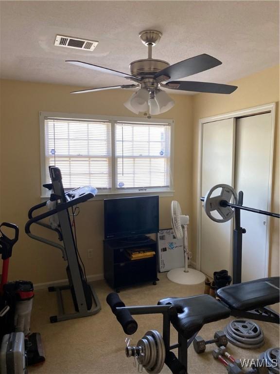 exercise room with a ceiling fan, a healthy amount of sunlight, visible vents, and light carpet