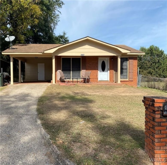 view of front facade featuring brick siding, fence, a carport, driveway, and a front lawn