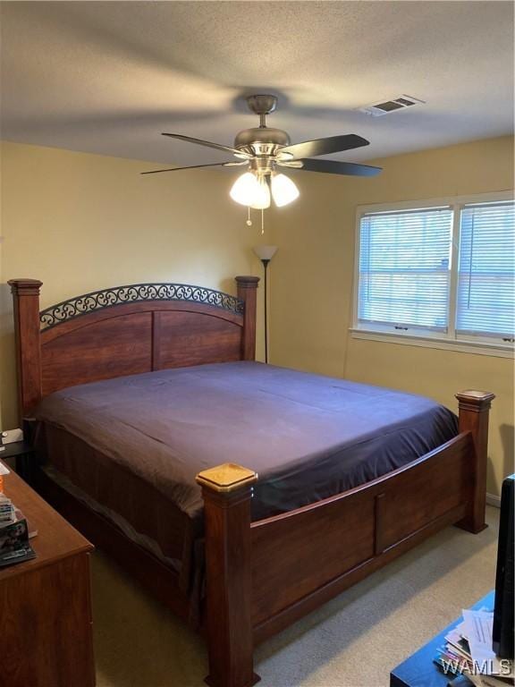 carpeted bedroom with a ceiling fan and visible vents