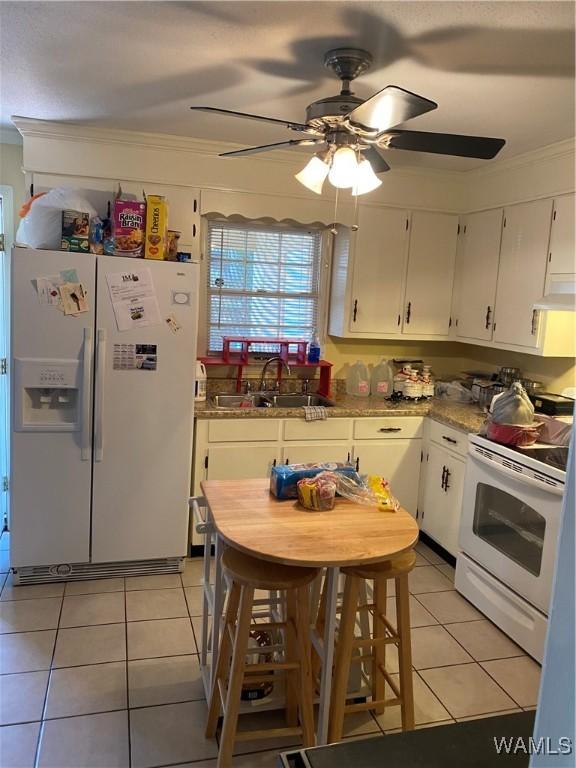 kitchen featuring white appliances, white cabinets, and light tile patterned flooring