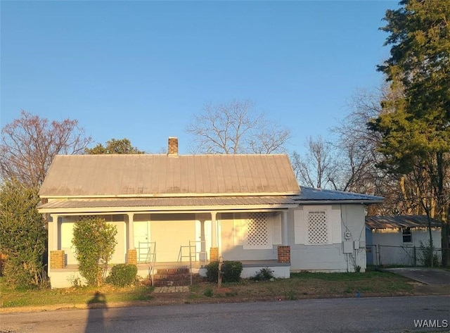 1923 18th Ave, Northport, AL 35476 - view of front of home with a porch, stucco siding, metal roof, and a chimney