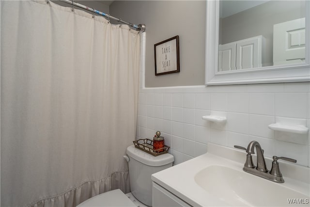 bathroom featuring vanity, toilet, and tile walls