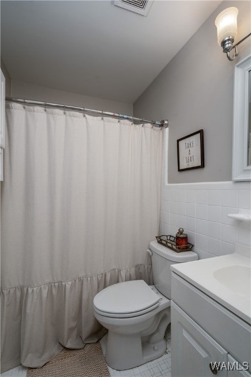 bathroom featuring tile patterned flooring, vanity, toilet, and tile walls