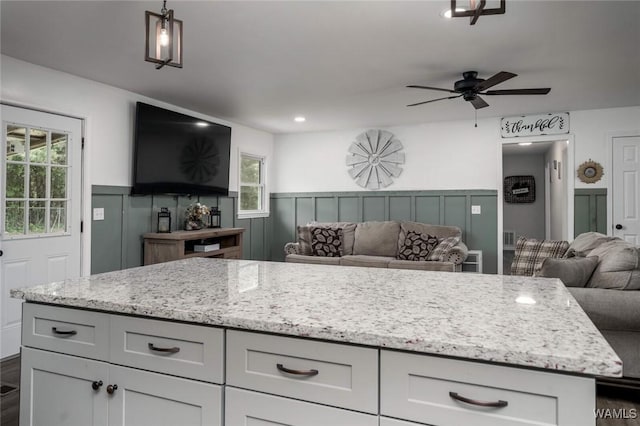 15120 Lakeland Forest Dr, Northport, AL 35475 - kitchen featuring open floor plan, a ceiling fan, light stone counters, decorative light fixtures, and a wainscoted wall