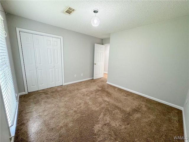 unfurnished bedroom with carpet, a textured ceiling, and a closet