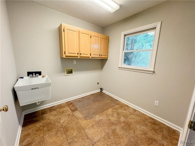 clothes washing area with sink, cabinets, washer hookup, tile patterned floors, and a textured ceiling