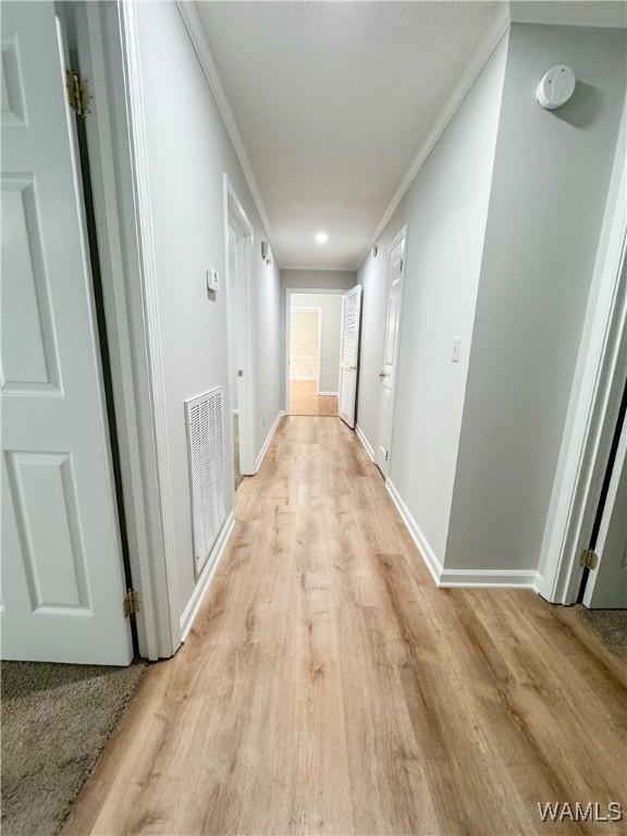 hallway featuring ornamental molding and light wood-type flooring