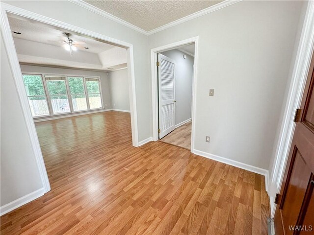 empty room with a textured ceiling, light wood-type flooring, ceiling fan, and ornamental molding