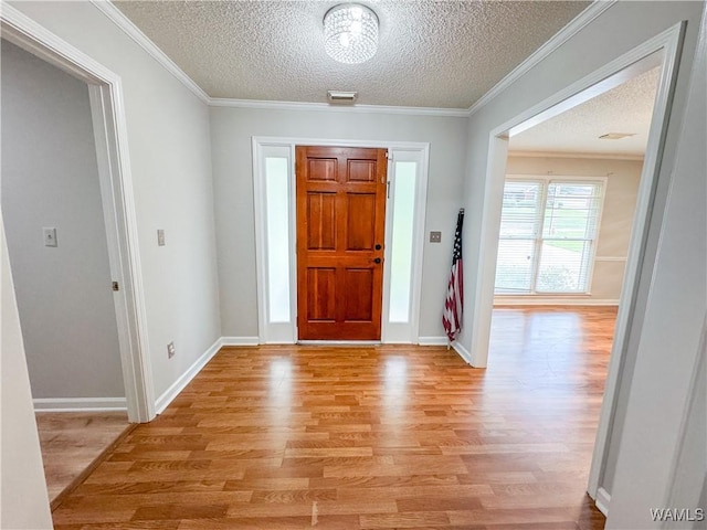 foyer with ornamental molding, a textured ceiling, and light hardwood / wood-style flooring