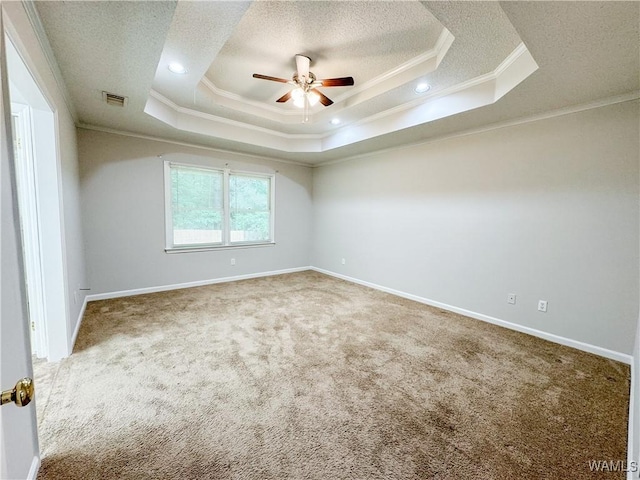 empty room featuring carpet flooring, ceiling fan, ornamental molding, and a tray ceiling