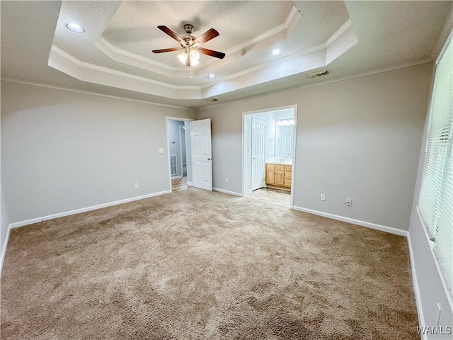 unfurnished bedroom featuring ceiling fan, a raised ceiling, crown molding, and connected bathroom