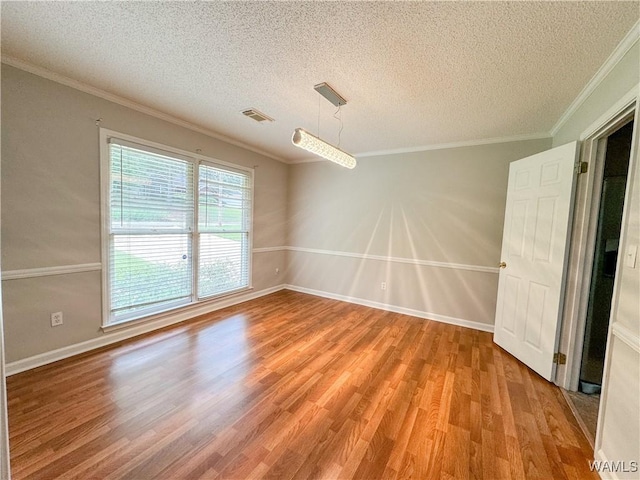 empty room featuring hardwood / wood-style floors, a textured ceiling, and crown molding