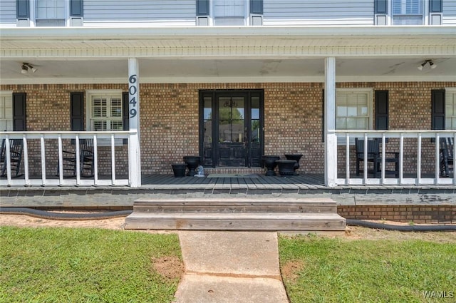 property entrance featuring covered porch and brick siding