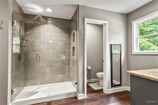 17631 Hayes Rd, Northport, AL 35475 - bathroom featuring toilet, a stall shower, wood finished floors, vanity, and baseboards
