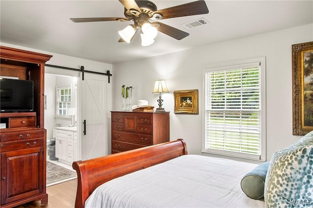2507 Twin Mnr, Northport, AL 35476 - bedroom featuring wood finished floors, a barn door, ensuite bathroom, and ceiling fan